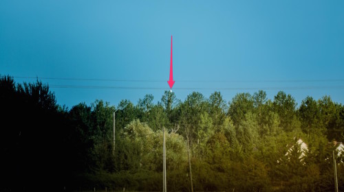 La flèche indique l'implantation de l'antenne qu'on devine derrière l'arbre